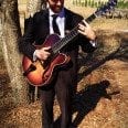 Taylor Roberts with guitar under tree March 2014