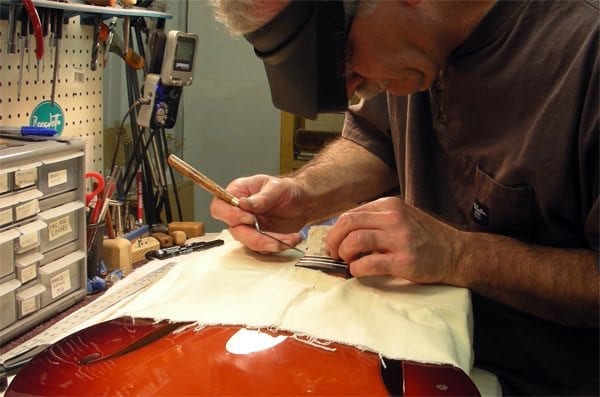 Luthier Rick Cervone removes tape from fingerboard in Final Assembly Benedetto Guitars 10-2-14